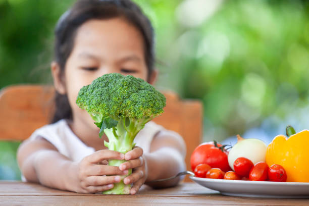 istock Cute asian child girl holding broccoli and learning about vegetables 1001955794