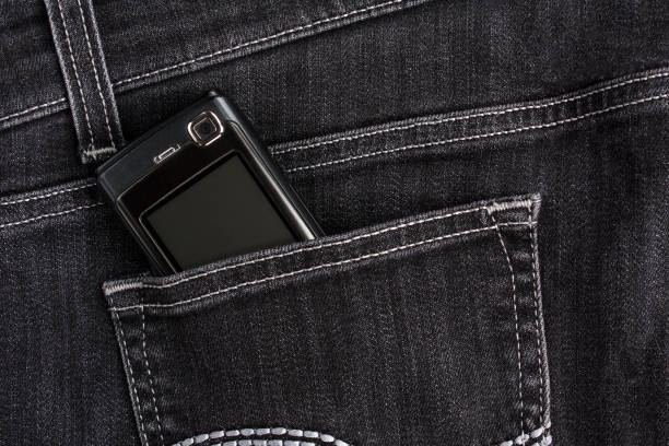 istock Old (push-button) mobile phone screen up in the back pocket of black jeans 1001966606