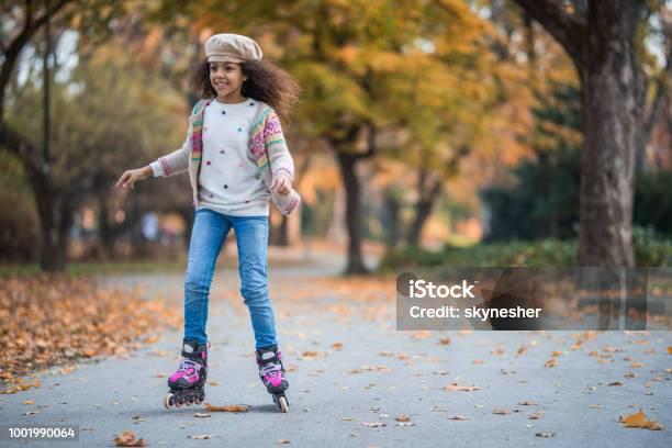 Happy African American girl having fun on her roller skates in the park.