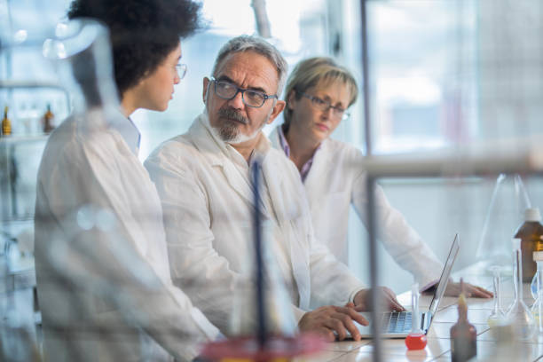 istock Group of biochemists talking while working on a research in laboratory. 1001996380