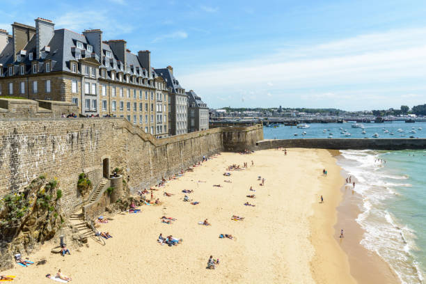 vista da praia mole, no sopé do rampart de saint-malo, frança, com gente tomando sol na areia, uma escada de pedra de acesso nos edifícios novos conhecimentos e granito atrás da parede. - bailey - fotografias e filmes do acervo