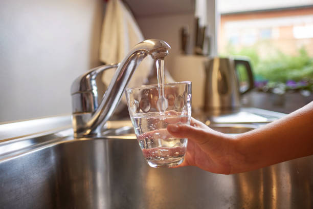 台所の水道の蛇口から新鮮な水のガラスを注ぐ、子供の手のクローズ アップ - faucet ストックフォトと画像