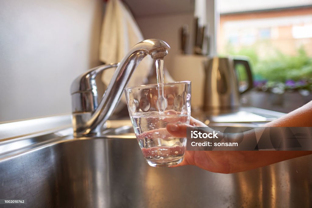 Close up of children hands, pouring glass of fresh water from tap in kitchen Pouring Fresh Tap Water Into a Glass Water Stock Photo