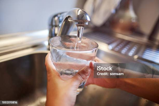 Close Up Of Children Hands Pouring Glass Of Fresh Water From Tap In Kitchen Stock Photo - Download Image Now
