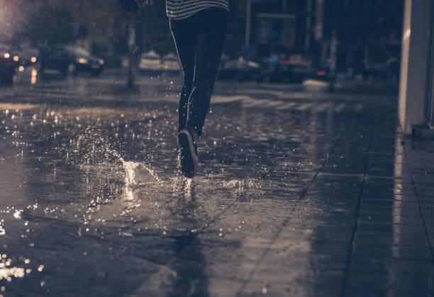 Rear view of unrecognizable person running on the street during rainy day.
