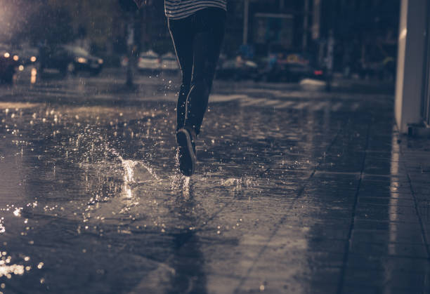 vista traseira da pessoa irreconhecível, correndo na chuva. - human leg women shower water - fotografias e filmes do acervo