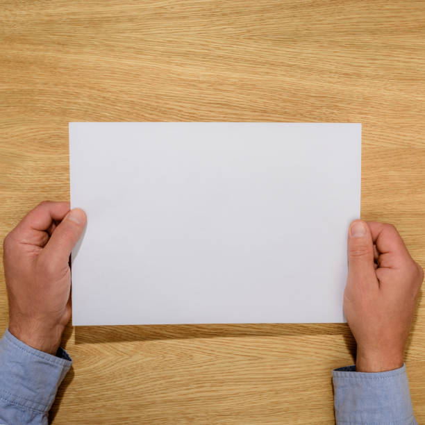 istock cropped image of man holding empty white paper over wooden table 1002014230