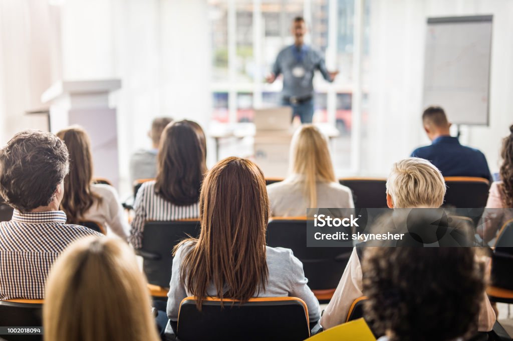 Rear view of business people attending a seminar in board room. Back view of large group of business people having a training class in a board room. Meeting Stock Photo