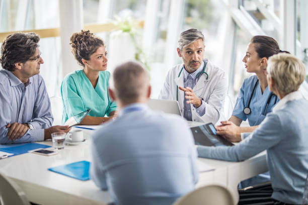 equipe de médicos e pessoas de negócios, falando em uma reunião no gabinete do médico. - doctor business person teamwork meeting - fotografias e filmes do acervo