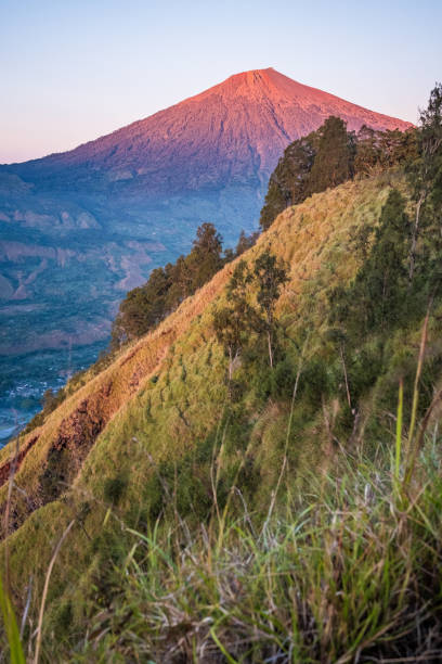The first rays of light striking the top of Rinjani Mountain.