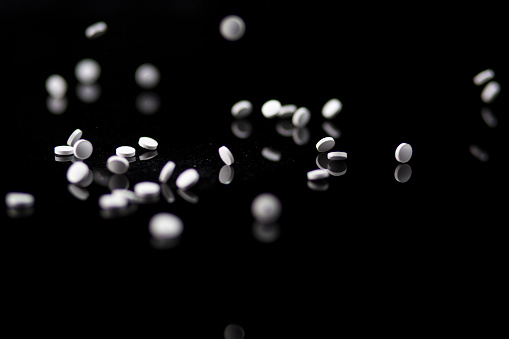 Close-up of white pills on black background.