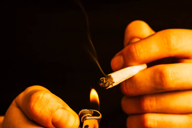 istock cannabis weed, a joint in his hands A man smokes . Smoke on a Yellow toning 1002024368
