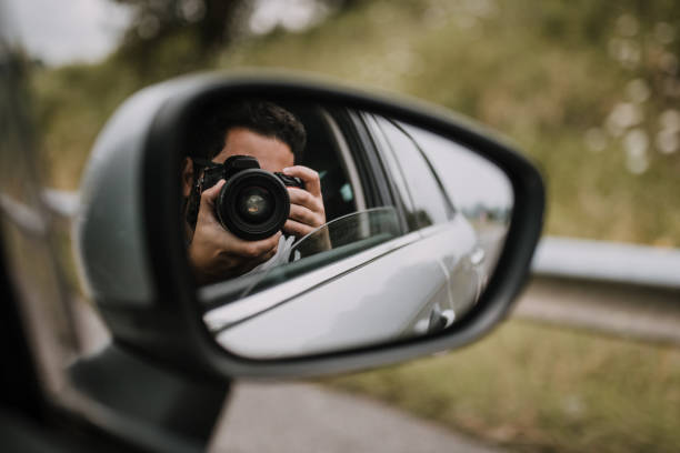 A young man taking a picture from a car