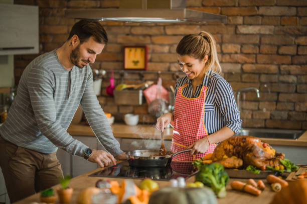 istock Young happy couple cooperating while cooking side dish for Thanksgiving dinner. 1002031190