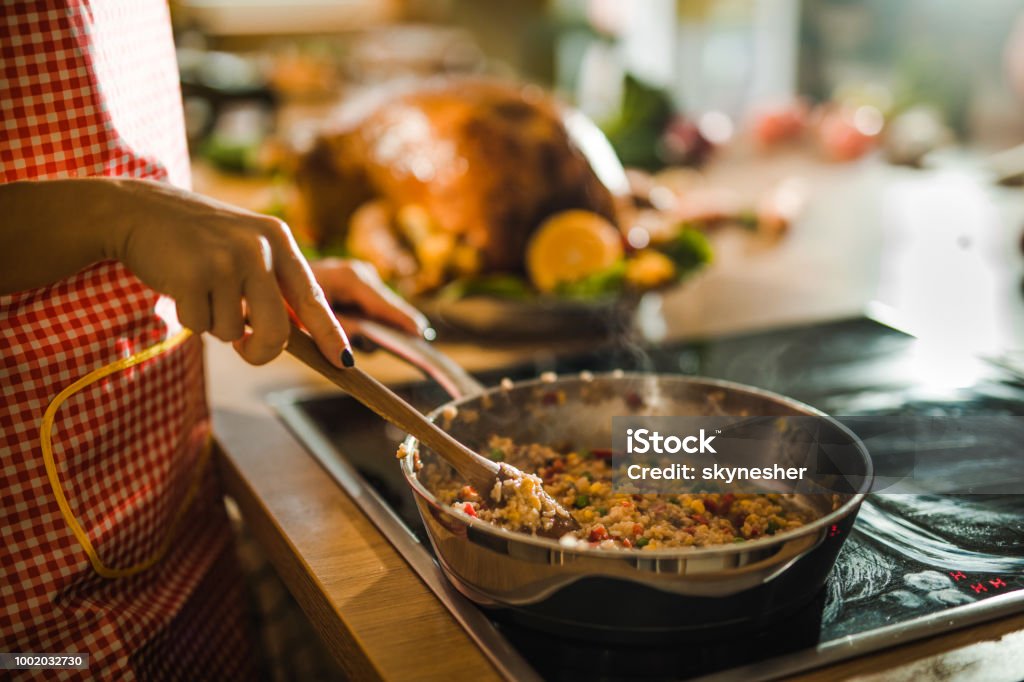 Unrecognizable woman preparing side dish for Thanksgiving dinner. Close up of unrecognizable woman preparing rice with vegetables for Thanksgiving dinner in the kitchen. Cooking Stock Photo
