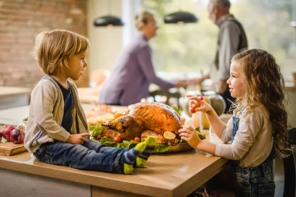 Photo of Cute little siblings talking on Thanksgiving day at their grandparents'.