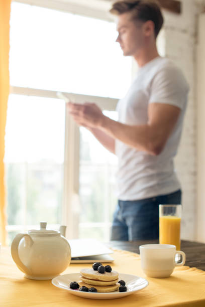 istock selective focus of breakfast on table and man using smartphone at home 1002041872
