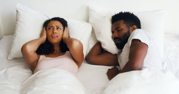 I love you but I wish the snoring could stop Cropped shot of a beautiful wife annoyed by her handsome husbands snoring in bed at home sleep apnea photos stock pictures, royalty-free photos & images