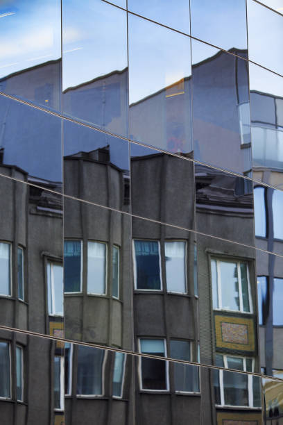 istock Fragmented facade of old building reflected in windows of modern office building 1002050602