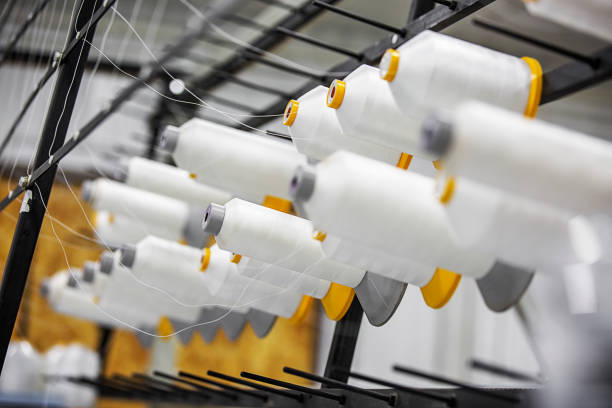 Textile factory. Equipment with spools of white yarn stock photo