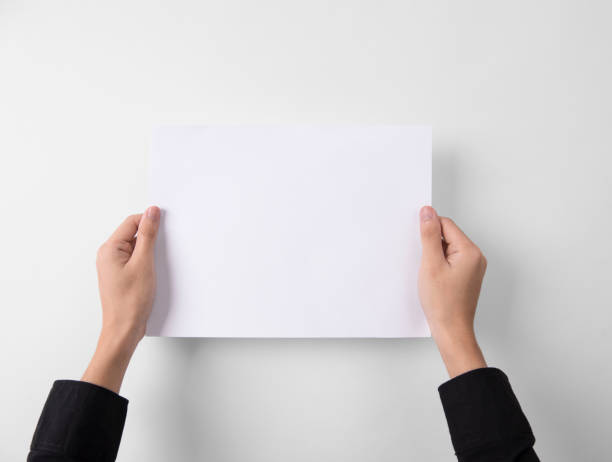 istock hand showing blank paper A4 flyer for mockup template logo branding on grey background. 1002053696