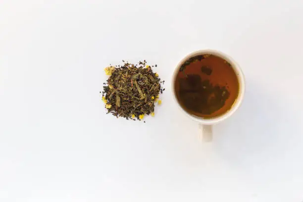 Cup of tea and dry herbal tea on a white background. Top view. Copy space
