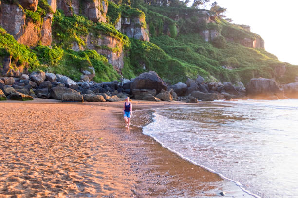 mujer madura caminando a lo largo de la costa - playa del silencio asturias fotografías e imágenes de stock