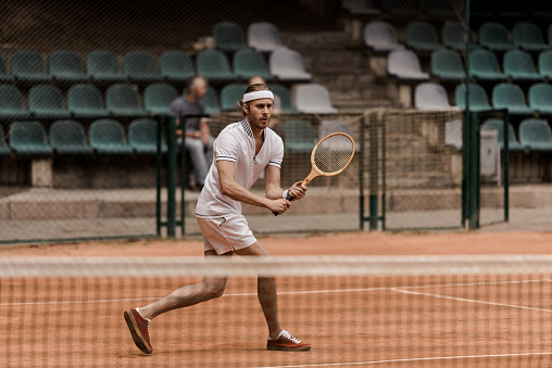 concentrated retro styled man playing tennis at court
