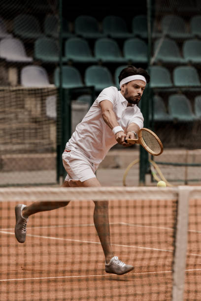 istock handsome retro styled man playing tennis at court 1002065240