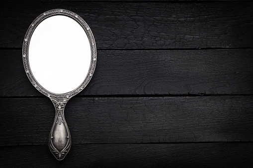 Hand mirror on dark background with space on text