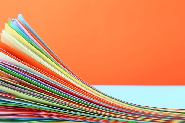 istock Stack of colored papers with paperclips on orange background 1002072180