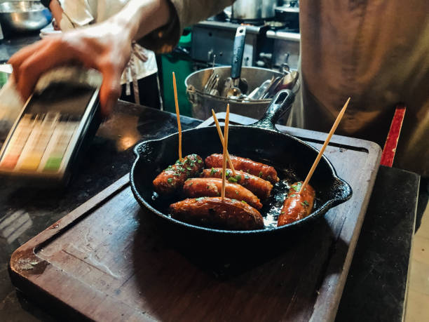 Sausages in frying pan on counter in restaurant ready for delivery and payment.