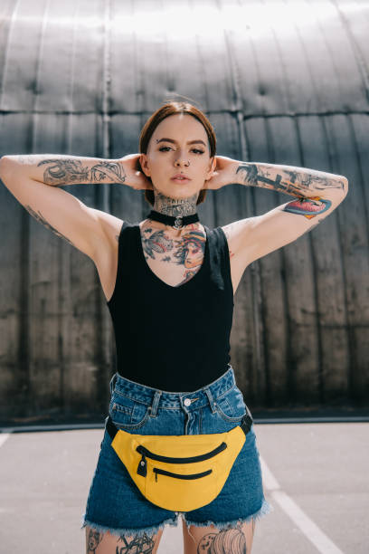 istock stylish young tattooed girl with wide arms looking at camera 1002079430
