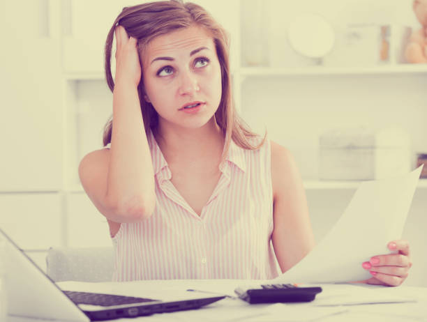 istock Young woman looking worriedly at bills 1002082966