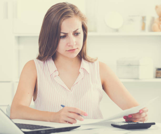 istock Young woman looking worriedly at bills 1002082974