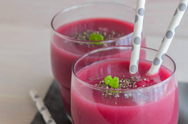 istock Red fruit raspberry smoothie in glass topped with chia seeds and mint on wooden table. Raw diet detox drink for health life. 1002083130