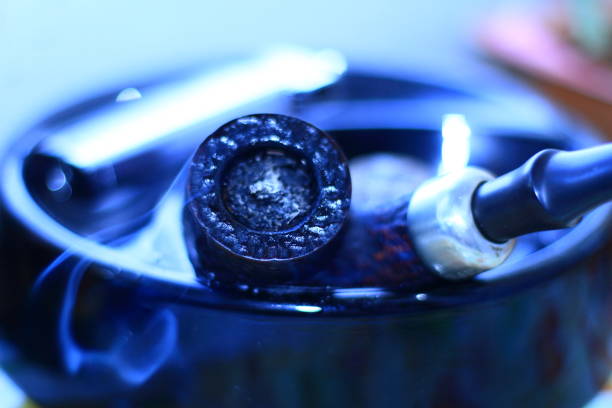 A smoking pipe in an ashtray and smoke.