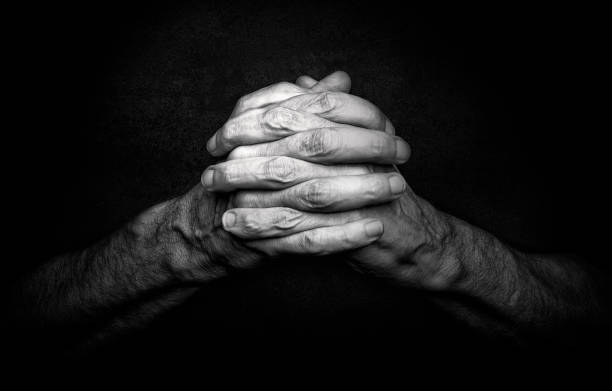 Mãos de homem a rezar - foto de acervo