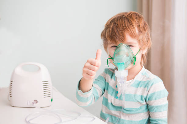 Little boy making inhalation with nebulizer at home. stock photo