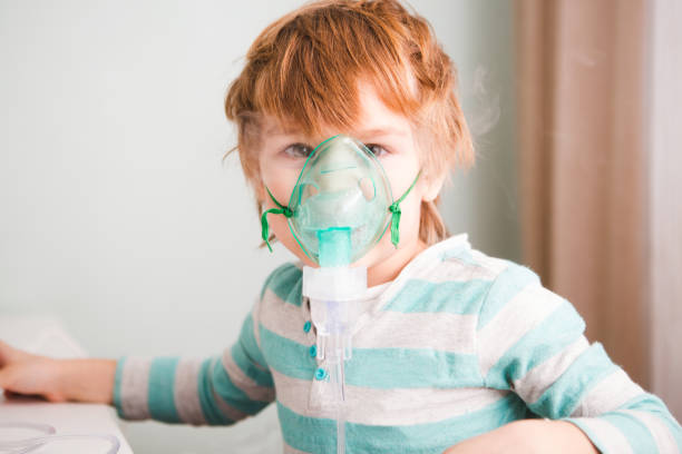 istock Little boy making inhalation with nebulizer at home. 1002090616