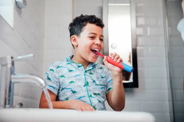 Little boy is brushing his teeth at the bathroom sink in the morning.