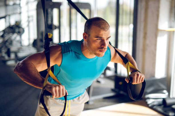 istock Man doing arm exercises with suspension straps at gym 1002094510