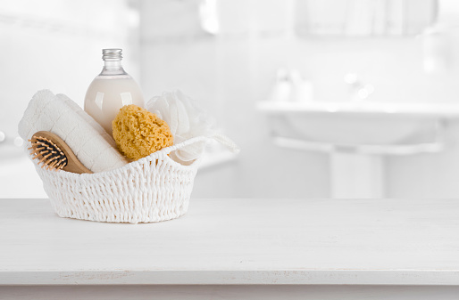 White basket with spa products on wooden table inside bathroom