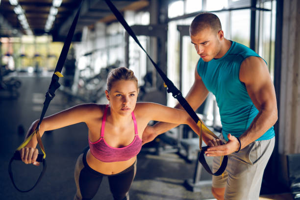 istock Woman doing arm exercises with suspension straps at gym 1002094816