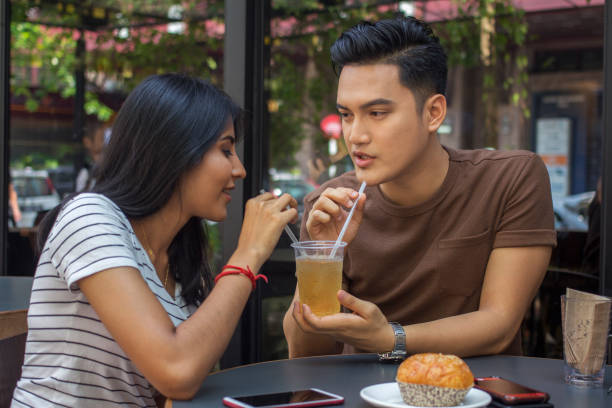closeup of young and trendy Mixed Race couple in relationship enjoying sweet time together talking, flirting and sharing a drink in a cafe stock photo