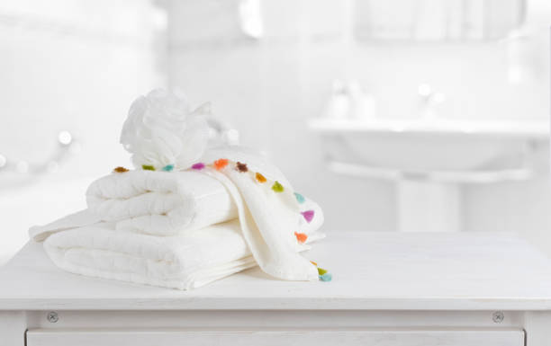 White cotton towels on wooden counter table inside bright bathroom