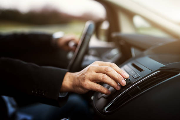 istock Businessman in suit is adjusting a volume on his stereo while driving a car. 1002100122