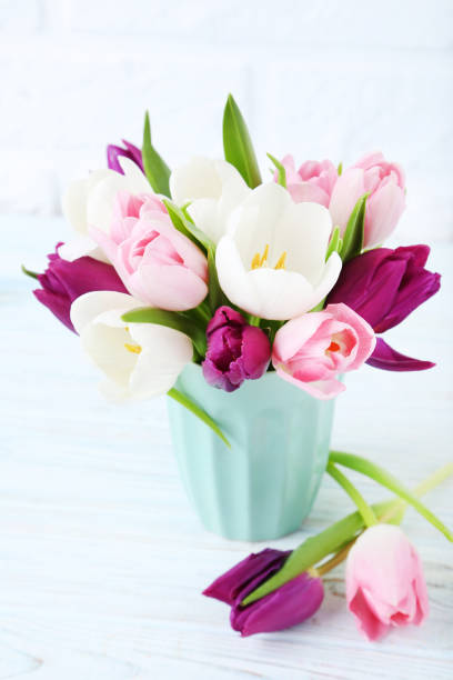istock Bouquet of tulips in cup on brick wall background 1002103300