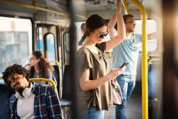 chica con gafas de sol en usar el teléfono mientras está parado en un autobús. - pasajero fotos fotografías e imágenes de stock