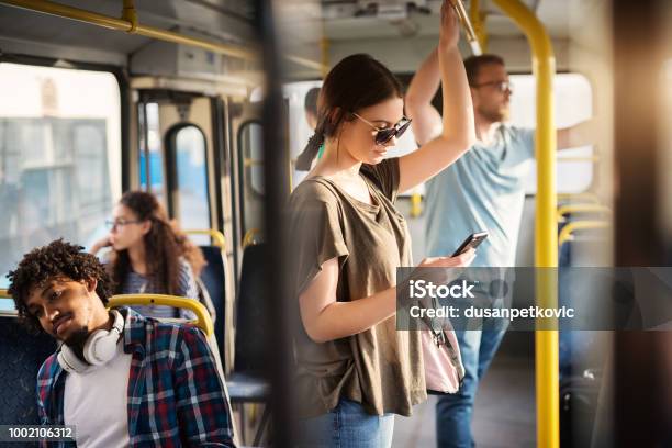 Sweet Girl With Sunglasses In Using Phone While Standing In A Bus Stock Photo - Download Image Now